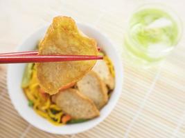 Yakisoba with chopstick and hand over bamboo pad photo