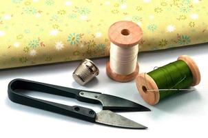Thimble,needle,spools and scissor with cloth for sewing on white background photo