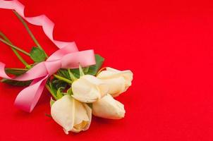 White roses bouquet with pink ribbon on red background photo