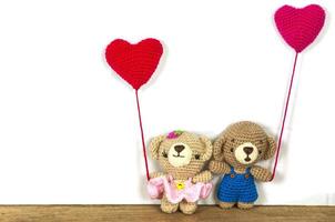 Lovely couple baby bears crochet doll holding heart shape balloon over wooden floor and white background photo