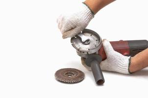 Worker is removing blade of angle grinder, hand tool, focus at blade and isolated over white. photo