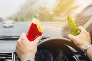 Man driving car while eating French fries and beer photo