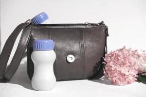 botella de plástico blanca junto al bolso y las flores. Bebida de colágeno o proteína para llevar. proteína líquida para el bienestar, la belleza de la piel y las articulaciones sanas. suplemento sanitario foto