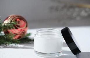 face cream in white jar next to christmas decor, new year sale or holiday present for women. sensitive face and skin care, cold protection cosmetic photo