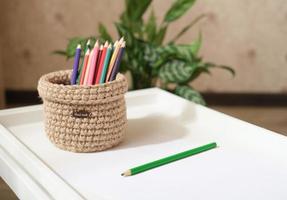 lápices de colores y canasta de mimbre tejida para guardar artículos de papelería. Cesta hecha a mano para pedido de escritorio. foto