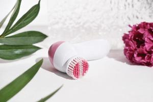 front view of pink electric facial cleansing brush. Cosmetic tool for face care, scrubbing, exfoliating, removing blackhead, massaging. self and beauty care routine device photo