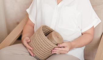 woman holding jute thread and wicker basket hande made with eco material. woven basket for storage. sustainable plastic free householding. photo