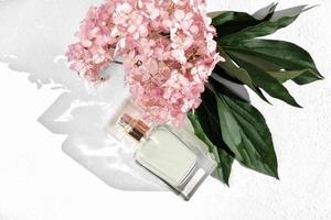 floral perfume fragrance. bottle of perfume with hydrangea flowers. unbranded product. flat lay. top view, photo