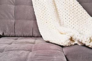 cozy plaid or knitted blanket on a modern sofa. cosy home concept. relaxing me-time, calm place to get rest and for stress relief. mind balance and inner peace photo