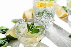 fresh lemon and mint drink in a glass cup. summer cold infused water for freshness. lime and lemon slices. healthy drinks for kids party photo