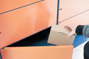 close up of a client using automated self service post terminal machine or locker to receive a parcel or to deposit the box. contactless delivery to pick up point photo