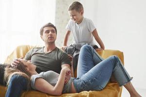 Happy family have fun on the yellow sofa in the living room of their new house photo