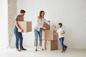 niño corriendo la familia tiene mudanza a una nueva casa. desempacar cajas de mudanza foto