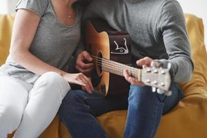 vista de partículas tocando la guitarra acústica para la novia en la sala de estar de la nueva casa foto