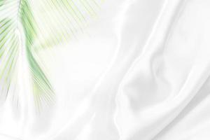 patrón de hojas de palma verde superpuesto con textura de tela blanca fondo borroso suave foto