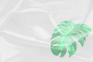 patrón de hojas de monstera verde superpuesto con textura de tela blanca fondo borroso suave foto