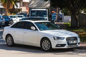 Antalya Turkey  March 04 2022   white  Audi A4  is parked  on the street on a warm  day against the backdrop of  park photo