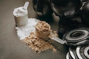 Scoop of protein powder with dumbbell background ,Fitness or healthy lifestyle concept. selective focus photo