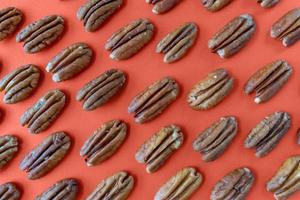 pecan halves arranged in pattern on fall orange background flat lay photo