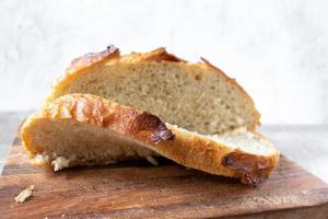 pan de masa fermentada en rodajas con bonitos picos de corteza en el bloque de carnicero foto