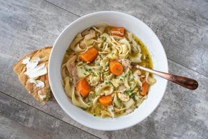 bowl of homemade chicken noodle soup with carrots flat lay photo