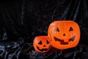 Two happy Halloween pumpkin pails on black velvet with copy space photo