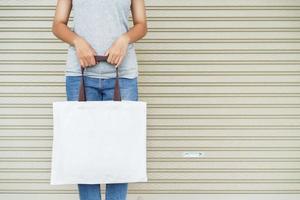 hipster woman holding white tote bag for mock up blank template photo