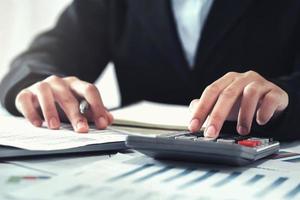 business accounting finance concept. accountant using calculator for calculate  with laptop working in office photo