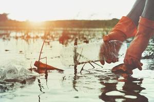 hand picking up garbage plastic for cleaning in river photo