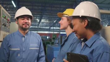 equipes profissionais multirraciais de engenheiros da indústria em capacetes e uniformes de segurança inspecionam os painéis de controle da máquina, verificam e mantêm na fábrica de fabricação mecânica, ocupações de serviços elétricos. video