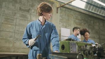 profissional jovem trabalhadora da indústria caucasiana trabalha em uniforme de segurança com ferramentas de precisão de metalurgia e máquinas de torno mecânico com equipe de engenheiros multirraciais na fábrica de fabricação de aço. video