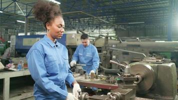 One professional young female industry engineer worker works in a safety uniform with metalwork precision tools, mechanical lathe machines, and spare parts workshop in the steel manufacturing factory.