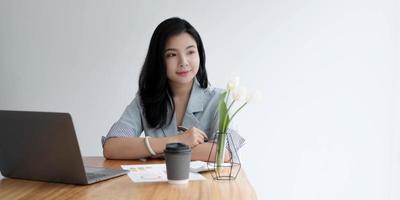 Asian business women sit in the office and drink coffee look laptop computer photo