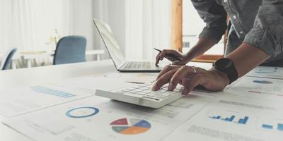 Business man working at office with digital tablet and laptop computer calculating financial report graph data documents on desk, close up, business analysis, work process concept photo