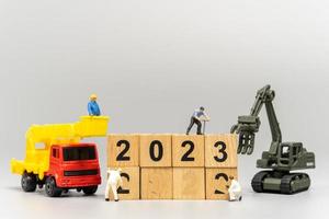 Miniature People Worker Team Create Number 2023 On Wooden Block photo