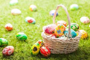 Unique hand painted Easter eggs in basket on grass photo