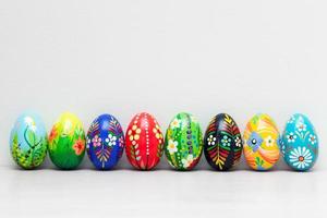 Hand-painted Easter eggs on white rustic wall. Spring patterns art. photo