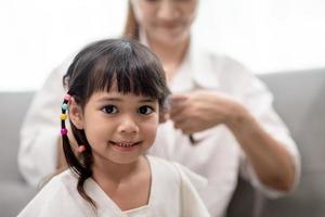 Young Asian mother tying daughter's hair photo