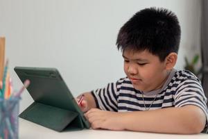 Kid self isolation using tablet for his homework,Child doing using digital tablet searching information on internet during covid 19 lock down,Home schooling,Social Distance,E-learning online education photo