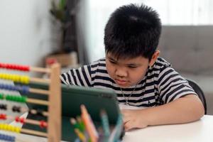 Kid self isolation using tablet for his homework,Child doing using digital tablet searching information on internet during covid 19 lock down,Home schooling,Social Distance,E-learning online education photo