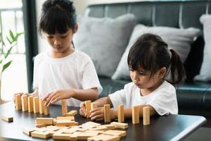 Two happy siblings playing a game with wooden blocks at home joyfully photo