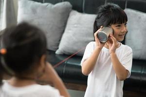 niños jugando con una lata y un teléfono de cuerdas como concepto de comunicación foto