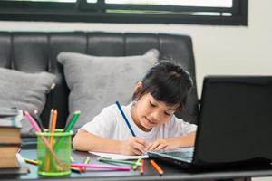 estudiante asiática clase de aprendizaje en línea estudio en línea videollamada profesora de zoom, niña feliz aprende inglés en línea con una computadora portátil en casa.nueva normalidad.covid-19 coronavirus.distanciamiento social.quédate en casa foto