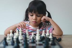 Asian little girl playing chess at home.a game of chess photo