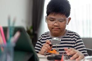 Young asia student remotely learn online at home  in coding robot car and electronic board cable in STEM, STEAM, mathematics engineer science technology computer code in robotics for kids. photo