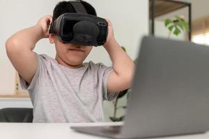 niño asiático con anteojos vr estudiando ciencias en casa, estudiante curioso usa un auricular de realidad virtual para estudiar ciencia en casa estudio en línea aprendizaje de estilo de vida futurista foto