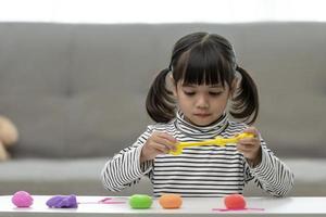 The little girl is learning to use colorful play dough in a well lit room photo