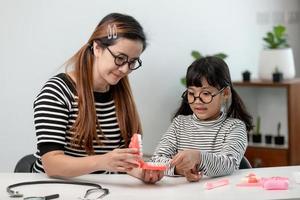 madre enseña a su hija a cepillarse los dientes con precisión foto