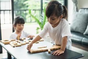 Two happy siblings playing a game with wooden blocks at home joyfully photo