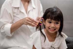 Young Asian mother tying daughter's hair photo